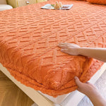 Une couverture de lit orange chaude et moelleuse avec un motif géométrique en relief.