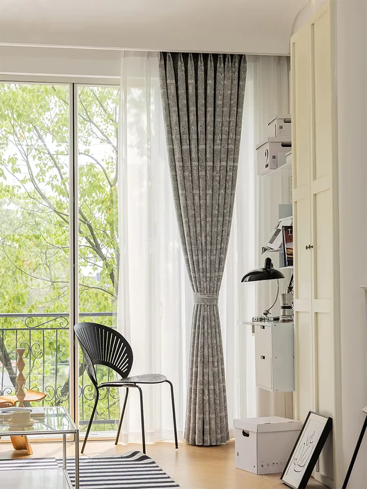Rideaux élégants gris pour salon moderne, style scandinave. Décoration intérieure avec lumière naturelle, grande baie vitrée, chaise design. Harmonie entre éléments contemporains et confort accueillant, accentuant la luminosité de la pièce. Convient pour un aménagement harmonieux et épuré.