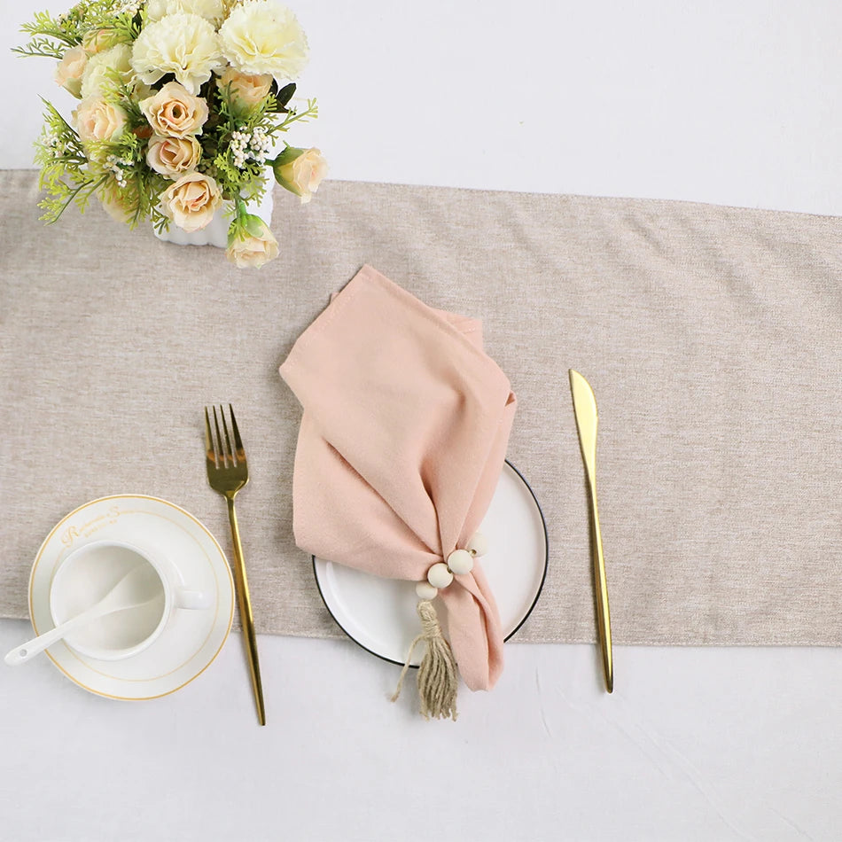 Une table élégante avec un bouquet de fleurs blanches et roses, une assiette et des couverts dorés, et une serviette de table rose nouée avec une décoration.
