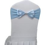 Une chaise blanche ornée d'un noeud en satin bleu clair, utilisée pour décorer une table de mariage ou un événement formel.