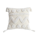 Coussin décoratif blanc moelleux avec des pompons et des glands.