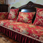 Ce canapé vintage au design baroque est recouvert d'un motif floral rouge et or, rehaussé de dentelle, offrant une atmosphère chaleureuse et élégante dans cet intérieur.