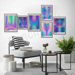 L'image montre une décoration murale composée de plusieurs affiches géométriques et psychédéliques dans des teintes de bleu, de violet et de rose, surplombant un coin salon avec un fauteuil gris rayé, une table basse et des éléments décoratifs.