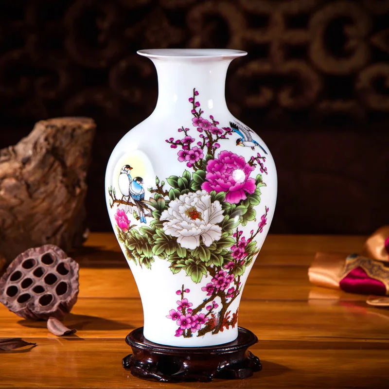 Un magnifique vase en porcelaine blanche orné de fleurs de pivoines et d'oiseaux multicolores, posé sur un socle en bois sombre.