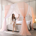 La photo montre une magnifique chambre à coucher décorée avec des rideaux et un lit à baldaquin, dans laquelle une jeune femme est assise sur le lit.