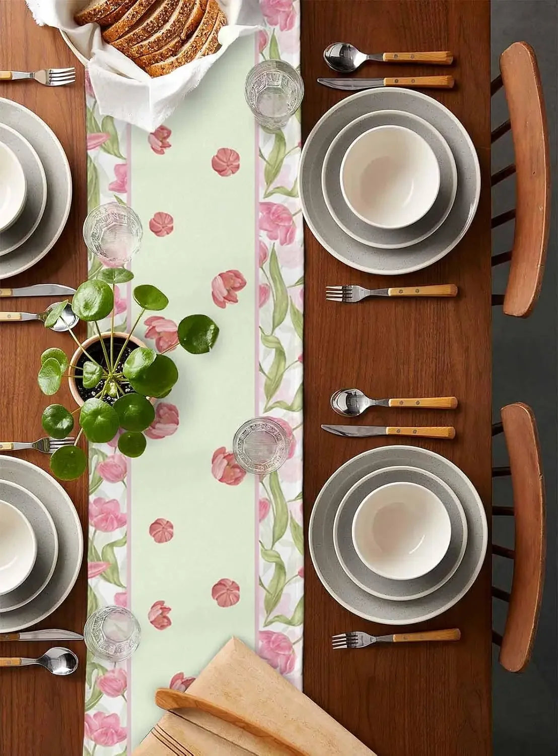 Ensemble de table élégant avec vaisselle blanche, couverts en bois et décoration florale sur un fond de bois foncé.