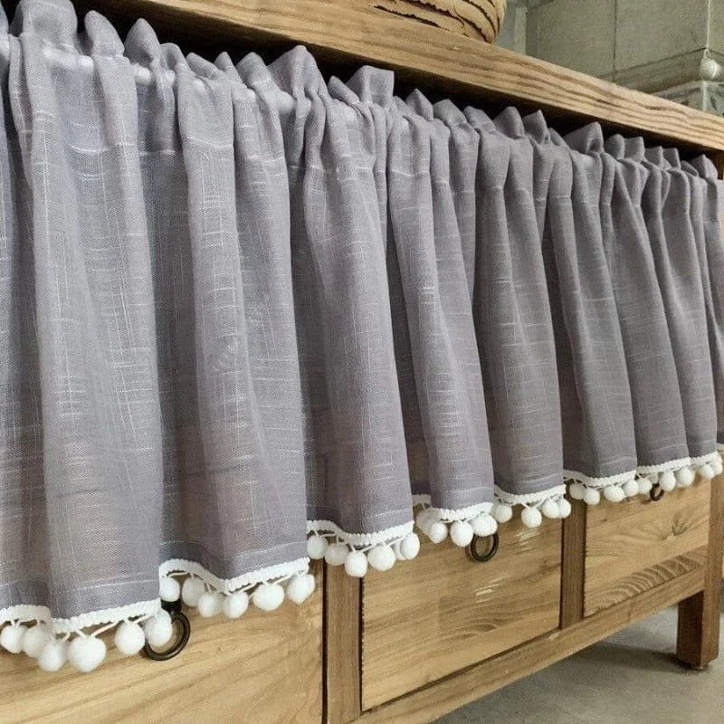 Rideau gris élégant avec pompons blancs, idéal pour ajouter une touche de charme à votre mobilier. Ce rideau décoratif est parfait pour une commode, une étagère ou une armoire, améliorant l'esthétique intérieure de votre maison. Conçu pour offrir une ambiance chaleureuse et accueillante, il s'intègre facilement dans tout type de décoration.