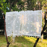 Rideau décoratif blanc avec motifs à pois et franges colorées suspendu à l'extérieur, idéal pour apporter une touche de fraîcheur et de légèreté à votre intérieur. Ce rideau tendance est parfait pour illuminer vos fenêtres tout en ajoutant une note de modernité et de joie à votre décoration. Adapté pour salon, chambre ou cuisine.