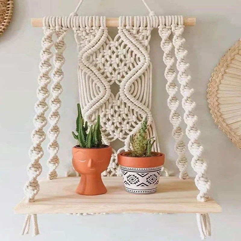 Étagère murale suspendue en macramé artisanale, idéale pour une décoration intérieure bohème. Présentée avec deux pots, l'un au design moderne sculpté en forme de visage, l'autre avec des motifs géométriques noirs et blancs, chacun accueillant des plantes succulentes. Parfaite pour ajouter une touche naturelle et artistique à votre espace de vie.