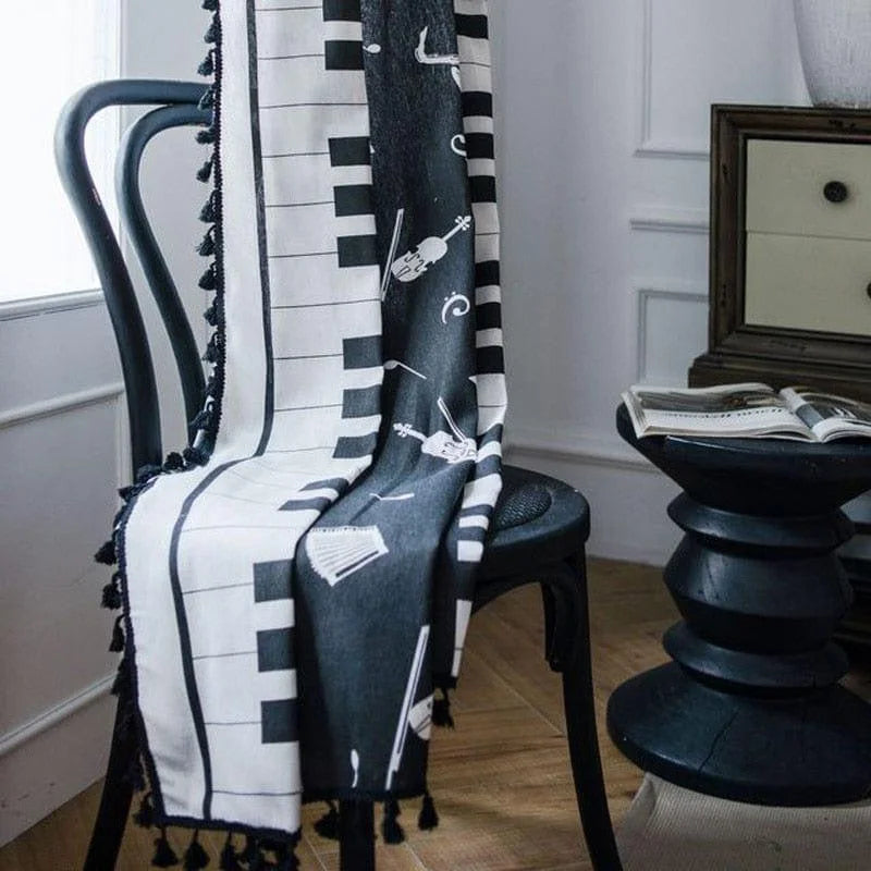 Plaid décoratif noir et blanc à motifs musicaux avec claviers de piano et instruments, idéal pour embellir un intérieur moderne. Élégant sur une chaise ou un canapé, il apporte une touche artistique et harmonieuse à votre salon. Parfait pour les amateurs de musique et de design contemporain.