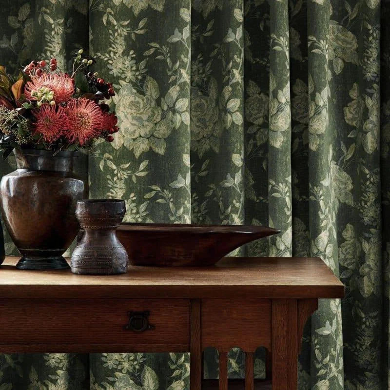 Rideau élégant à motifs floraux verts, ajoutant une touche de sophistication et de charme à votre intérieur, vu derrière une table en bois avec des vases décoratifs. Idéal pour apporter une ambiance naturelle et apaisante à votre salon ou chambre.