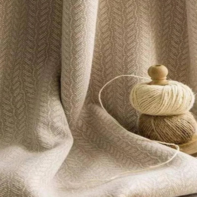 Tissu beige texturé avec pelotes de fil beige et marron posées à côté. Idéal pour la décoration intérieure ou des projets de couture. Élégant et sobre, ce tissu s'intégrera parfaitement dans un environnement moderne ou traditionnel grâce à son motif discret et raffiné. Parfait pour concevoir des rideaux ou des nappes qui ajoutent une touche de chaleur à votre espace.