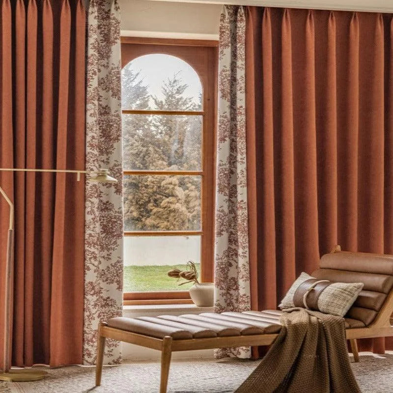 Rideaux élégants marron et imprimés avec motifs floraux, habillant une grande fenêtre en arche pour une décoration intérieure raffinée, accompagnés d'un fauteuil moderne confortable et d'une lumière naturelle apaisante.