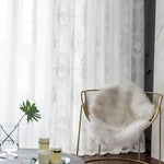 Fauteuil élégant avec couverture moelleuse blanche, placé près de rideaux transparents ornés de motifs délicats. Idéal pour un salon moderne et raffiné. Ambiance cosy avec table basse décorative. Luminosité naturelle apportant une douceur à la pièce.