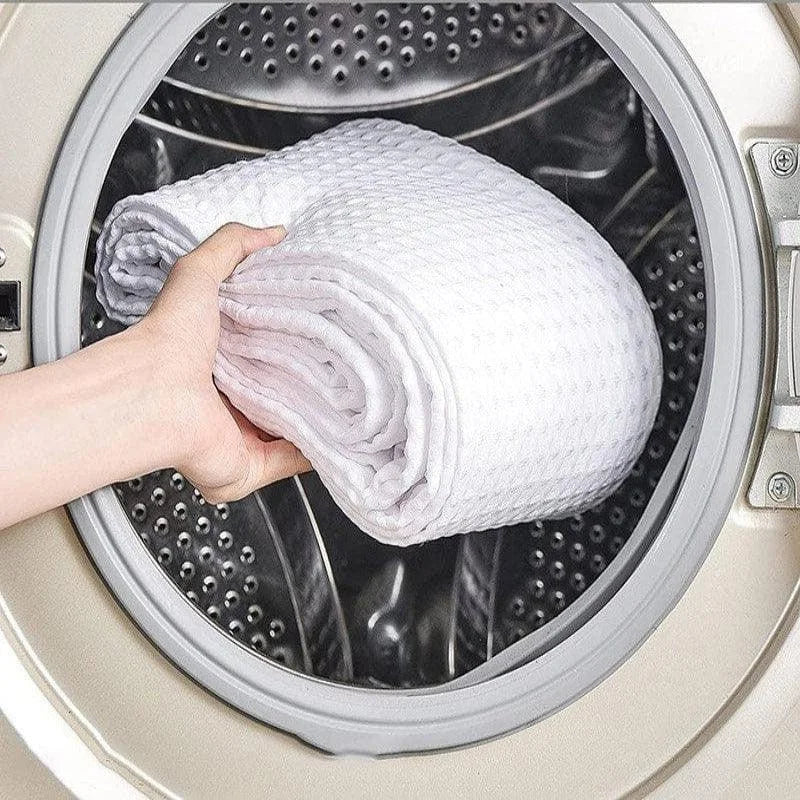 Rouler une couverture blanche prête à entrer dans une machine à laver, montrant sa praticité et facilité d'entretien. Image présentant une solution efficace pour le lavage des grandes pièces textiles domestiques. Idéal pour ceux recherchant des textiles faciles à nettoyer.