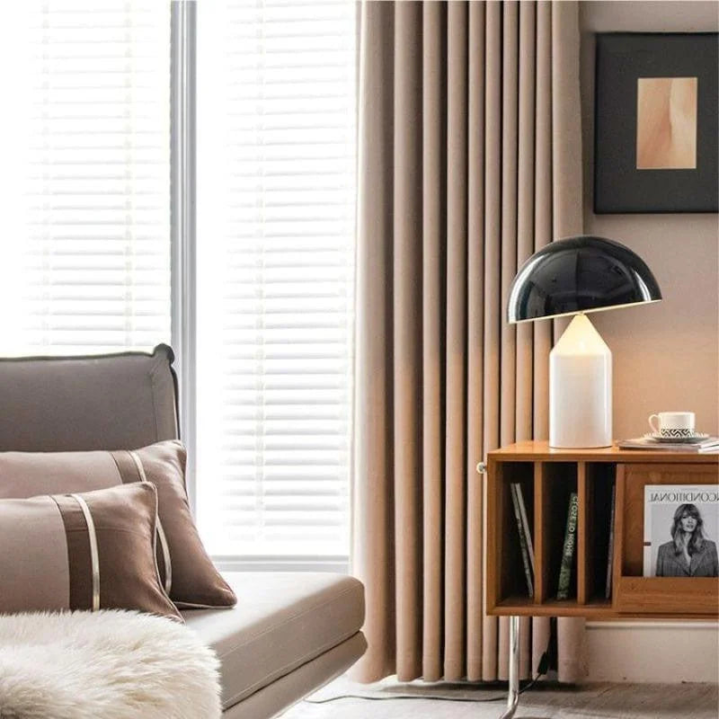Chambre moderne et élégante avec rideaux beige, canapé confortable agrémenté de coussins assortis et petite table d'appoint en bois. Lampe de table au design contemporain pour une ambiance cosy. Décor minimaliste avec une attention aux détails esthétiques.