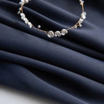 Image d'un tissu bleu foncé, délicatement orné d'un élégant bracelet de petites fleurs blanches, parfait pour créer une ambiance raffinée et sophistiquée dans vos créations textiles ou vos aménagements d'intérieur.