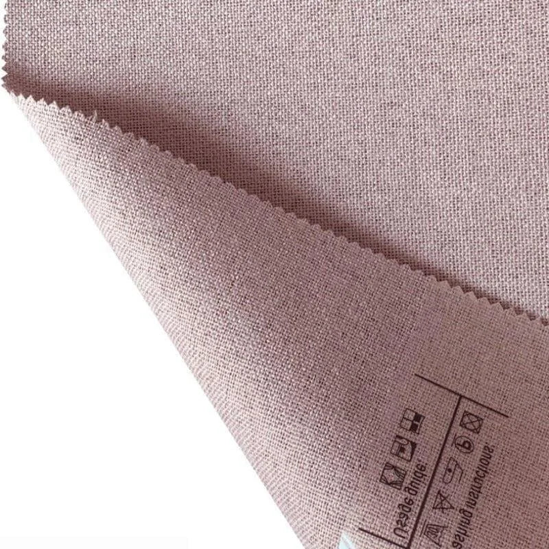 Échantillon de tissu rose clair avec une texture tissée, parfait pour la confection de rideaux ou de coussins décoratifs dans un intérieur moderne. Conseils d'entretien visibles au dos.
