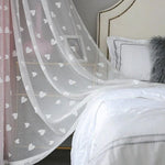 Voilage décoratif à motifs de cœurs blanc, idéal pour une chambre à coucher élégante. Ce rideau ajoute une touche romantique et subtilement moderne à votre intérieur. Accompagne parfaitement une literie claire et des oreillers stylés pour un effet apaisant.