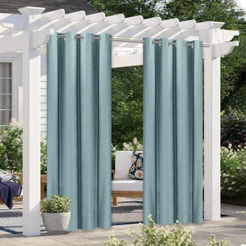 Rideaux d'extérieur bleus suspendus à une pergola blanche dans un jardin, offrant une ambiance élégante et intime pour les espaces extérieurs.