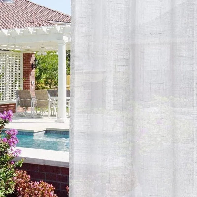 Voilage blanc pour terrasse extérieure apportant élégance et intimité à vos espaces. Idéal pour protéger du soleil tout en préservant la vue sur la piscine et le jardin fleuri. Parfait pour une décoration raffinée et moderne.