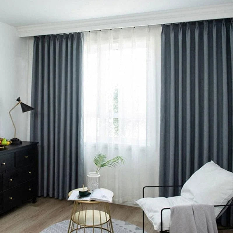 Rideaux occultants gris élégants dans un salon moderne avec lumière naturelle, mobilier contemporain et décoration minimaliste pour un intérieur chic et fonctionnel.