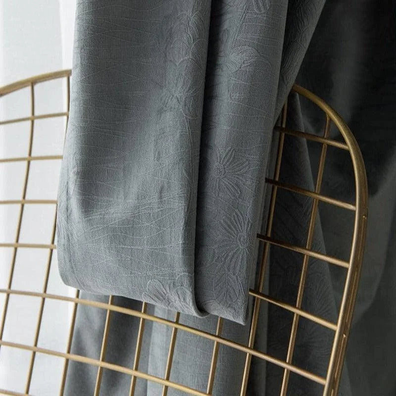 Rideau élégant gris anthracite avec motif floral, drapé sur une chaise métallique dorée. Accessoire parfait pour ajouter une touche de sophistication et de modernité à votre espace intérieur.