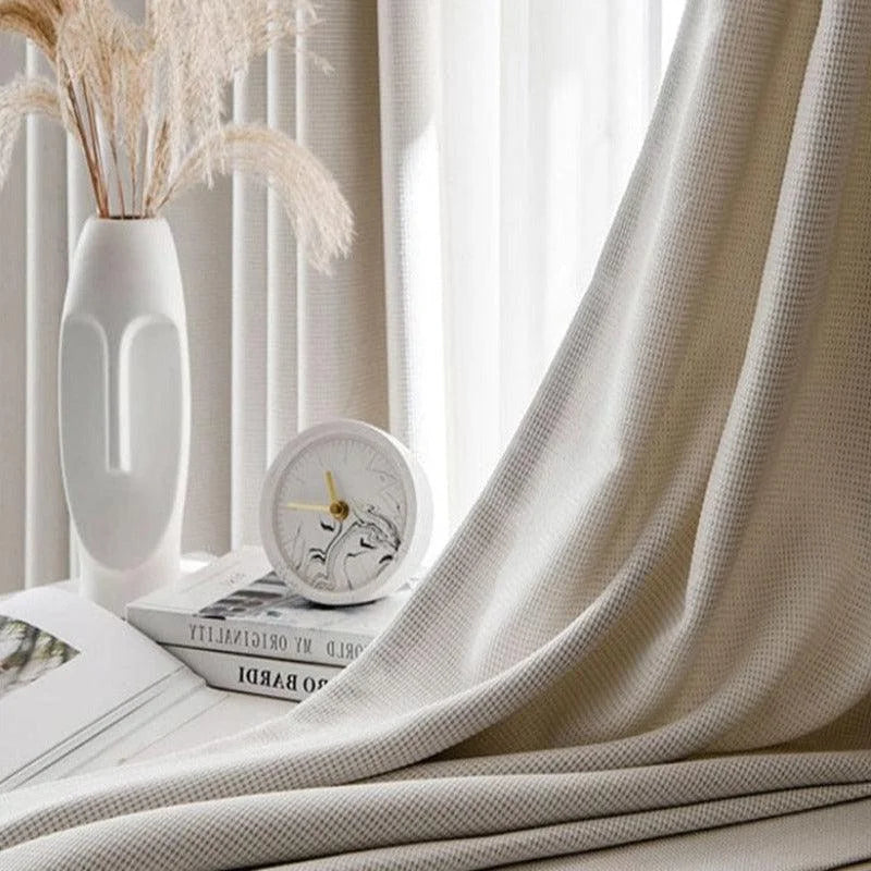 Rideau élégant couleur crème dans une décoration épurée. Idéal pour ajouter une touche de sophistication à votre intérieur. Accompagné d'une horloge design et d'un vase moderne, ce rideau embellit votre espace tout en filtrant délicatement la lumière naturelle. Parfait pour un salon chaleureux ou une chambre paisible.