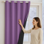 Femme touchant un rideau thermique violet doublé de tissu matelassé noir, suspendu à une tringle à œillets devant une fenêtre hivernale.