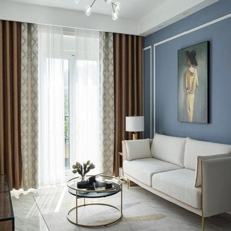 Salon moderne et élégant avec un canapé contemporain blanc, table basse circulaire en verre, et rideaux géométriques marron et blancs. Design intérieur raffiné avec des murs bleus, accentué par un tableau artistique. Luminosité naturelle grâce à de grandes fenêtres. Ambiance chic et chaleureuse pour un espace de vie accueillant.