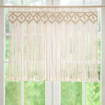 Rideau en macramé suspendu devant une fenêtre, idéal pour décorer votre intérieur avec une touche bohème. Parfait pour créer une ambiance chaleureuse et filtrer la lumière douce du soleil. Accessoire de décoration tendance pour toutes les pièces de la maison.