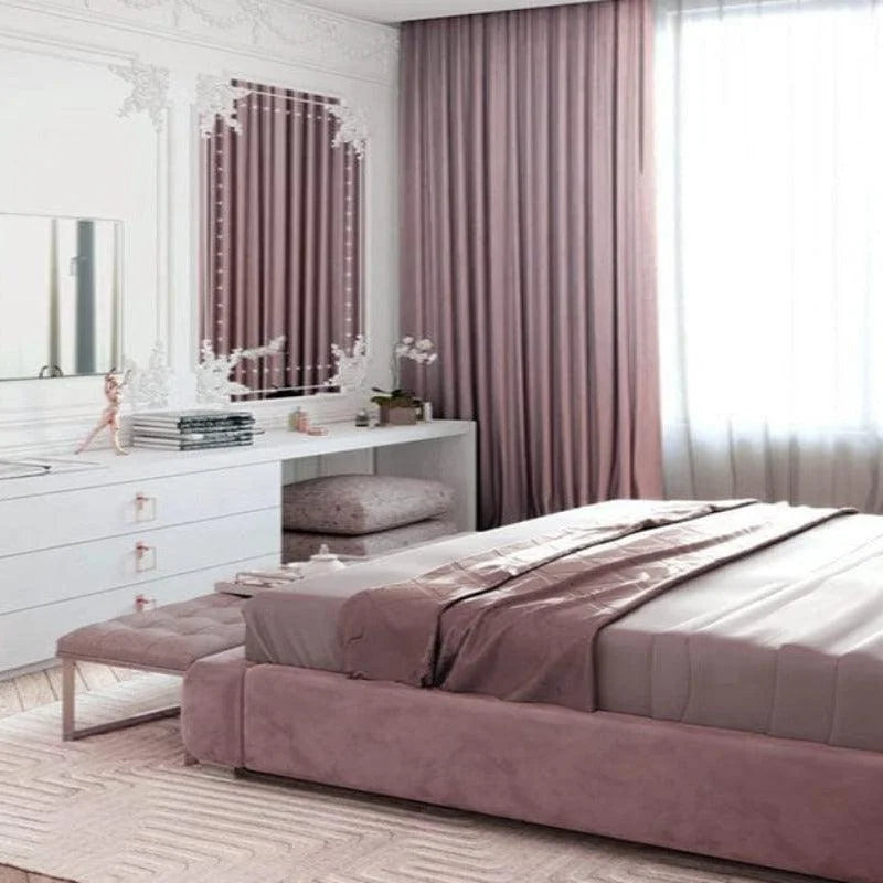 Chambre élégante avec décoration raffinée, comprenant un lit double capitonné, des rideaux assortis, et un meuble de coiffeuse blanc avec miroir orné. Atmosphère relaxante et lumineuse, parfaite pour un intérieur moderne et cosy. Idéale pour les aménagements de chambres contemporaines.