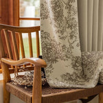 Rideau élégant à motifs floraux sur chaise en bois tressé, créant une ambiance chaleureuse et naturelle dans une maison lumineuse. Parfait pour ajouter une touche de style à votre intérieur tout en préservant l'intimité lumineuse.