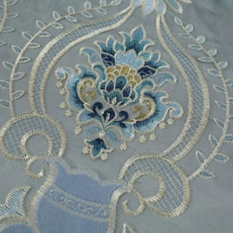 Motif floral élégant avec broderie raffinée en tons de bleu et beige, idéal pour une décoration intérieure sophistiquée. Design ornemental complexe et harmonieux, parfait pour ajouter une touche de luxe à tout espace de vie.