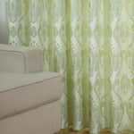 Rideau décoratif vert clair à motifs baroques avec canapé beige, idéal pour salon, apportant élégance et style à votre intérieur moderne.