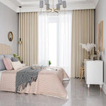 Chambre moderne avec literie élégante et décoration raffinée. Grand lit avec tête de lit rembourrée, draperies longues encadrant une fenêtre pour une ambiance lumineuse. Mobilier chic et accessoires décoratifs, tels que coussins variés et luminaire contemporain, créent un espace paisible et accueillant pour un intérieur stylé et confortable.
