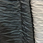 Image montrant des tissus plissés de couleur noire et blanche, disposés côte à côte, mettant en évidence un contraste élégant. Idéal pour la décoration intérieure ou les projets de couture, ces textures uniques ajoutent une touche moderne et sophistiquée.
