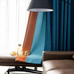 Rideaux élégants en bleu et marron pour salon moderne, combinés à un canapé chic et un éclairage contemporain, ajoutant une touche sophistiquée à l'ambiance intérieure. Décoration raffinée et tendance idéale pour un espace accueillant et chaleureux.