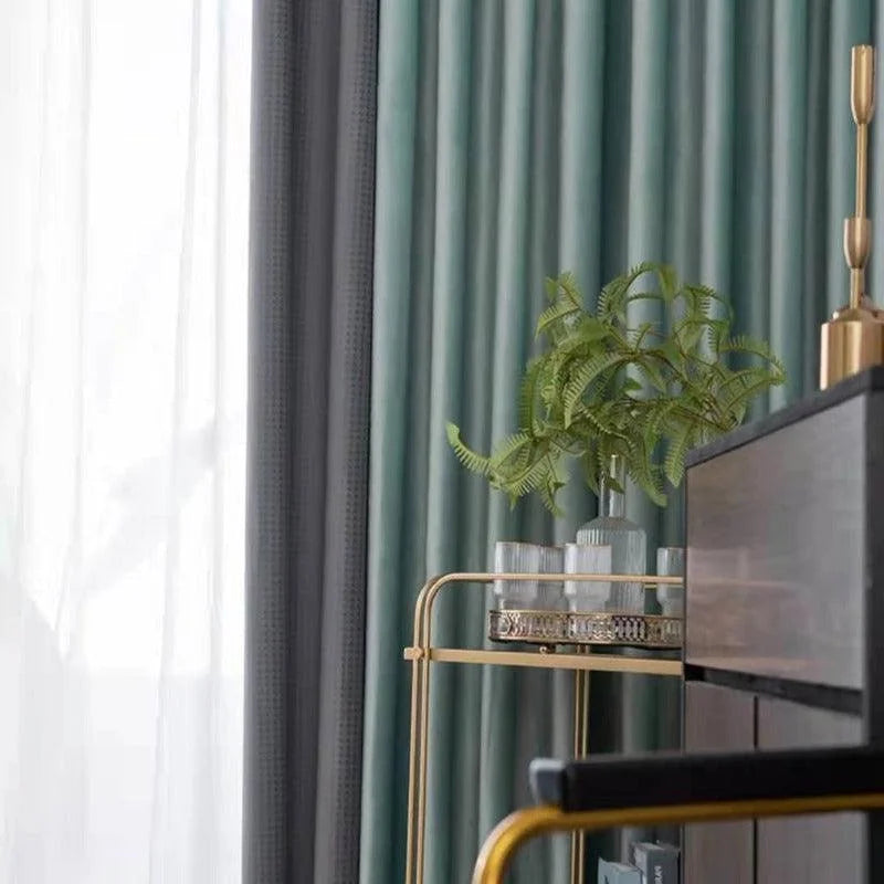 Rideaux élégants avec dégradé de couleurs grises et vertes pour une ambiance raffinée. Beau meuble doré avec plante décorative ajoutant une touche de verdure et de modernité à l’intérieur. Idéal pour salon chic et contemporain. Créez un espace accueillant avec ces éléments de décoration intérieure sophistiqués.