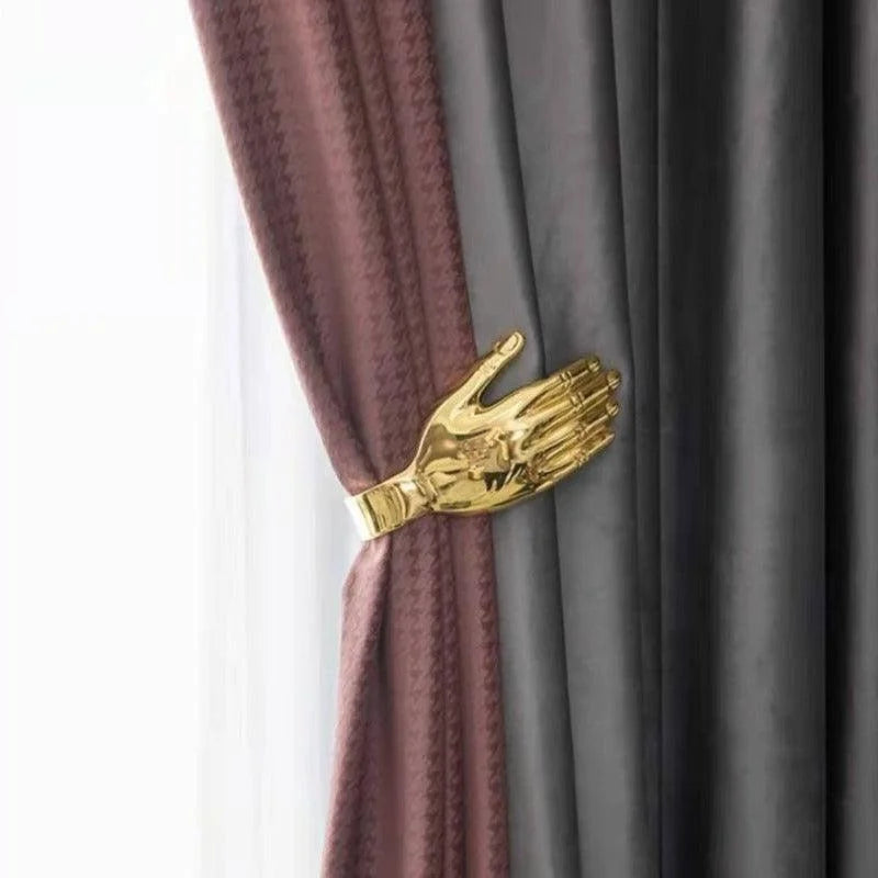 Attache-rideau originale en forme de main dorée tenant des rideaux élégants, ajoutant une touche artistique et moderne à votre décoration intérieure. Accessoire pratique et décoratif pour sublimer vos fenêtres. Idéal pour un salon, une chambre ou un bureau.