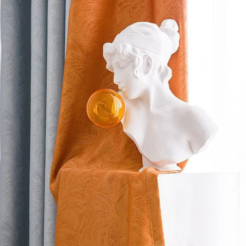 Buste décoratif moderne à bulles dans un intérieur élégant, accentué par des rideaux orange et gris. Accessoire unique pour sublimer votre décoration intérieure avec une touche artistique et contemporaine. Idéal pour les amateurs de design innovant et sophistiqué.