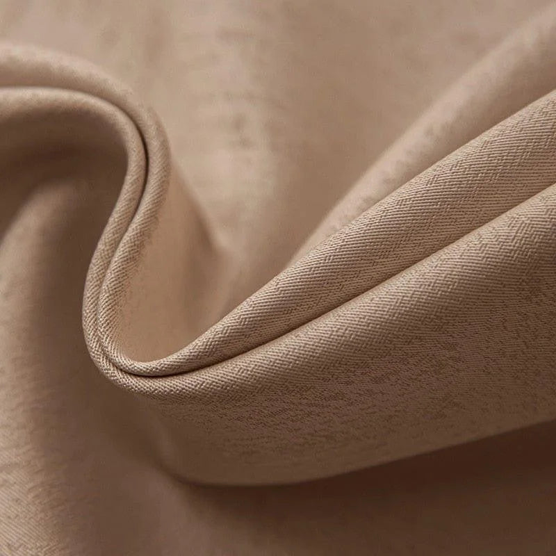 Texture élégante d'un tissu beige en gros plan, révélant un motif subtil et raffiné. Parfait pour la décoration intérieure ou la confection de vêtements, ce tissu offre une finition luxueuse et sophistiquée. Idéal pour ajouter une touche de classe et de confort à tout espace.