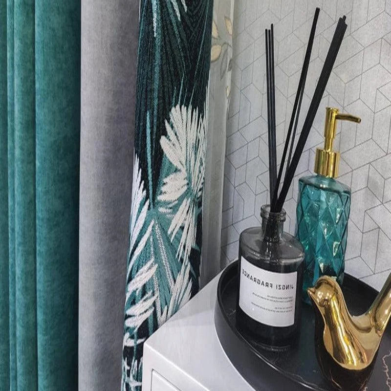 Ensemble élégant de décoration intérieure : rideaux avec motif floral vert et blanc, flacon de parfum d'ambiance et distributeur de savon doré sur plateau noir, le tout placé contre un mur au design géométrique, parfait pour une touche sophistiquée à votre espace.