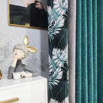 Rideaux élégants bleu canard avec motifs de feuilles tropicales, apportant une touche d'élégance moderne à votre intérieur. Ils encadrent un coin décoratif avec une sculpture artistique et un meuble blanc, idéal pour créer une ambiance chic et apaisante dans votre salon ou chambre. Parfait pour une décoration intérieure raffinée.