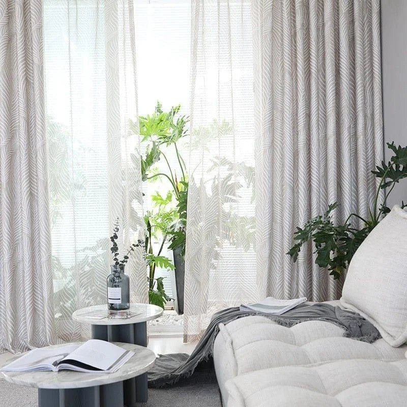 Salon moderne avec rideaux élégants et plantes vertes, mettant en valeur une ambiance lumineuse et naturelle. Les tables basses rondes apportent une touche contemporaine, offrant un espace accueillant pour la détente et la lecture.
