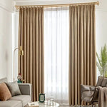 Rideaux élégants couleur beige dans un salon moderne, apportant une touche sophistiquée à la décoration intérieure. Les rideaux tombent gracieusement du plafond au sol, encadrant une grande fenêtre. Le salon est orné de meubles contemporains avec un canapé beige, une lampe dorée et des plantes vertes pour un espace accueillant et harmonieux.