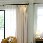 Rideaux élégants pour salon moderne avec décoration raffinée, mettant en valeur un fauteuil confortable jaune et un coussin géométrique. Lumière naturelle abondante et ambiance chaleureuse pour un espace de vie accueillant. Découvrez comment ces rideaux ajoutent une touche de sophistication à votre intérieur.