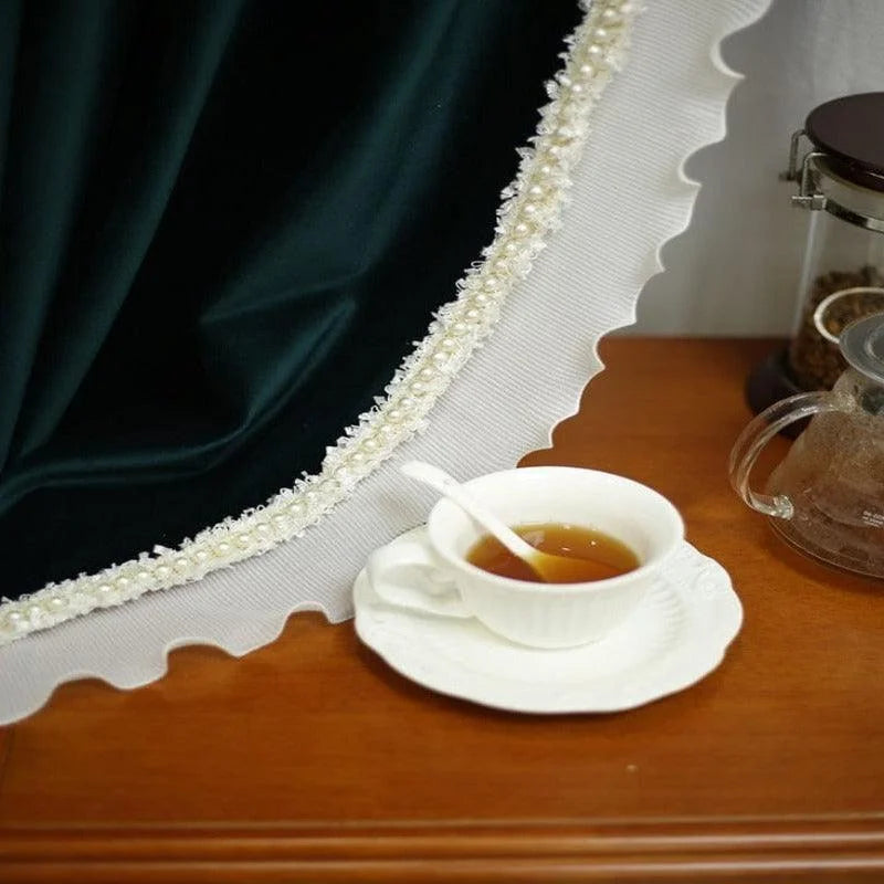 Tasse de thé élégante posée sur une soucoupe blanche, accompagnée d'une théière transparente, près d'un rideau décoratif en dentelle. Moment de détente et raffinement pour apprécier une pause thé réconfortante. Idéal pour les amateurs de décor intérieur chic et délicat.