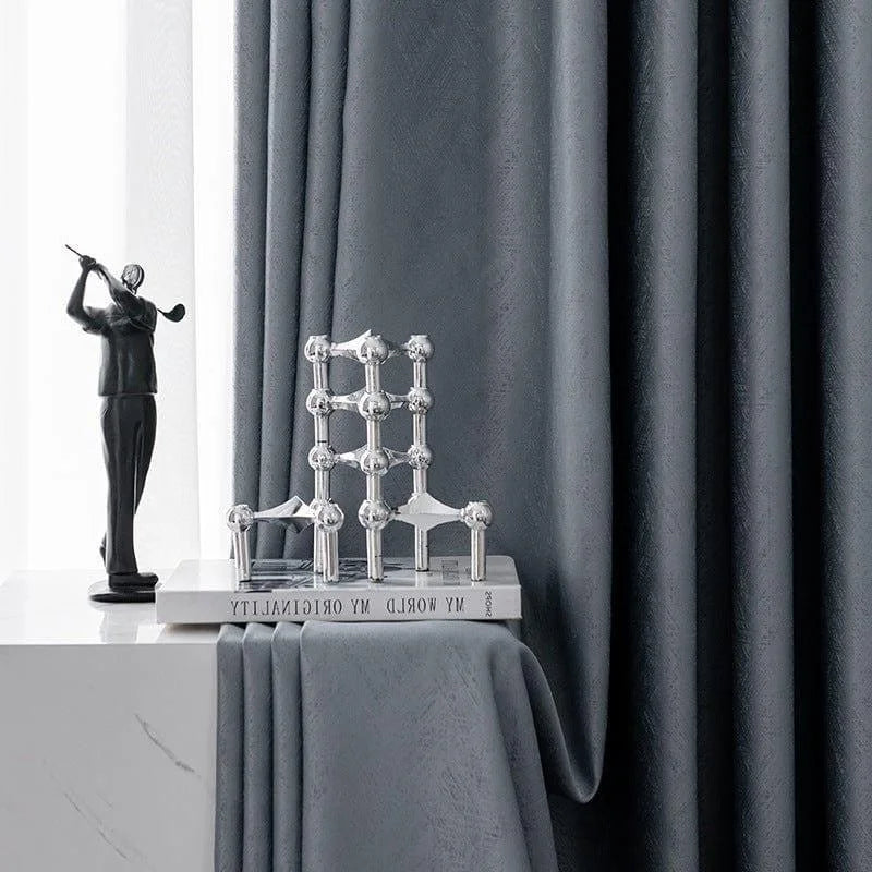 Rideaux élégants de couleur grise, parfaits pour ajouter une touche moderne et sophistiquée à votre intérieur. Accessoirisés avec une sculpture décorative et un livre posé sur une table, ces rideaux créent une ambiance chic et contemporaine dans n'importe quelle pièce de la maison.