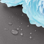 Gouttelettes d'eau sur surface imperméable avec belles fleurs bleues, illustrant l'efficacité d'une protection contre l'humidité. Idéal pour les produits d'extérieur et les accessoires résistants aux intempéries.